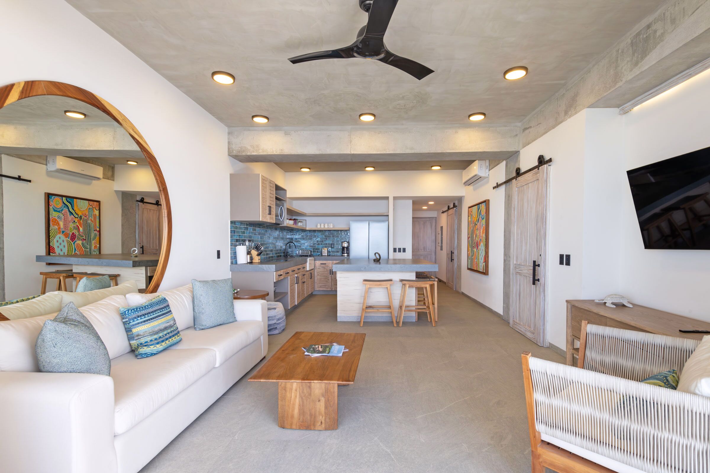 Un salon moderne avec un canapé blanc, une table basse en bois et un grand miroir.