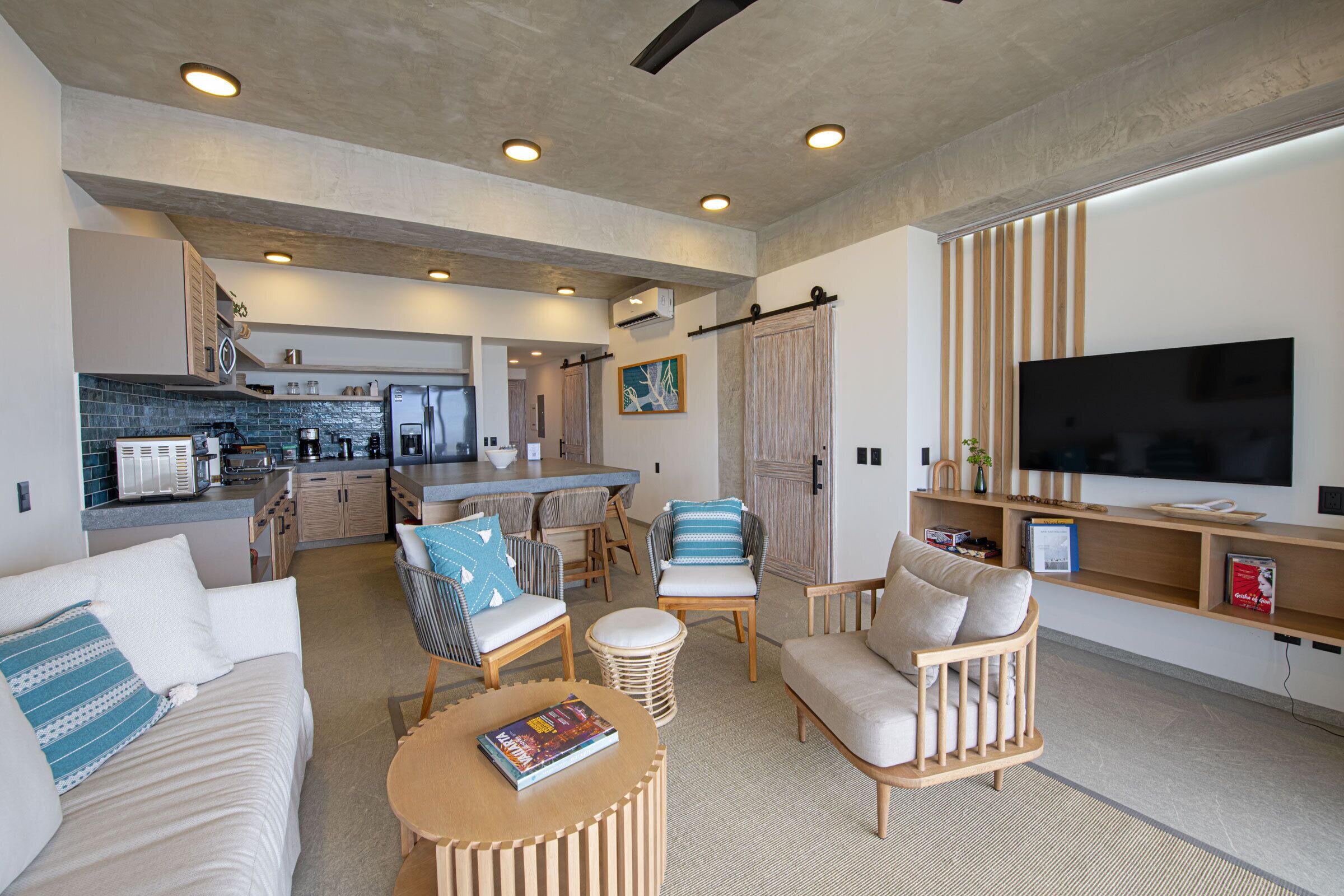 A modern living room with a sofa, chairs, a coffee table, and a TV.