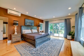 A bedroom with a large bed, wooden floor, and a view to the outside. - Secluded Ithaca Home w/ Hot Tub ~ 5 Mi to Cornell! (Ithaca)