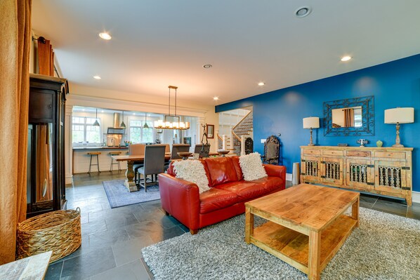A spacious living room with a red leather sofa, wooden coffee table, and a blue accent wall. - Secluded Ithaca Home w/ Hot Tub ~ 5 Mi to Cornell! (Ithaca)