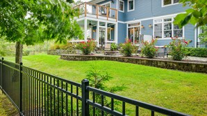 Een twee verdiepingen tellend huis met een balkon, een stenen muur en een verzorgd gazon.