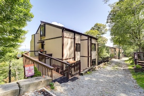 A two-story building with a wooden deck and a gravel path leading to the entrance.