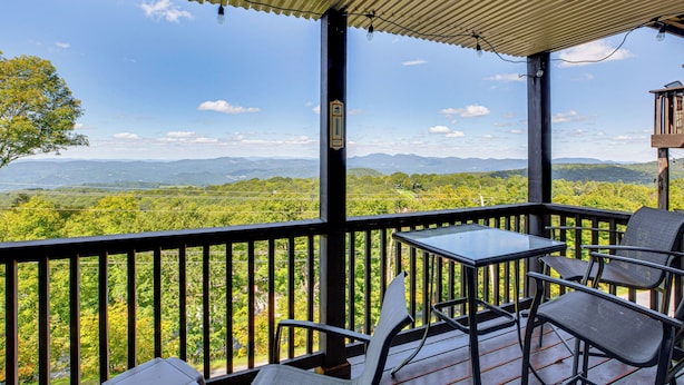 A balcony with a table and chairs, overlooking a lush landscape with mountains in the distance. - Hike, Ski & Fish! Sunset-View Condo in Beech Mtn (Beech Mountain)