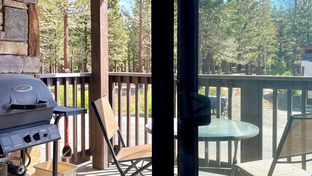 A covered outdoor area with a grill, seating, and a view of trees. - Fireside Condo at the Village - Sleeps 4 - Newly Remodeled (Mammoth Lakes)
