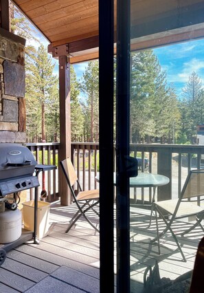 Un espacio al aire libre techado con una parrilla, asientos y vistas a árboles.