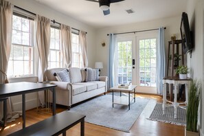 Un salon avec un canapé, une table basse et un téléviseur fixé au mur.