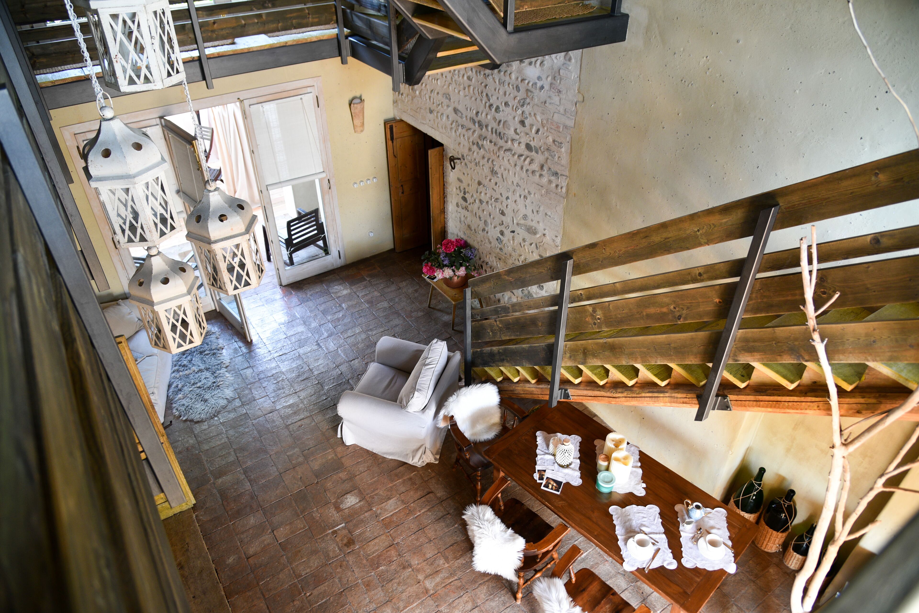 A spacious room with a wooden floor, a dining table set with tableware, a sofa, and a staircase.
