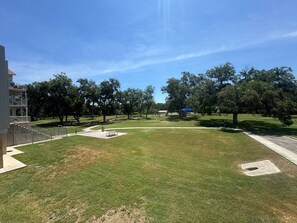 A grassy area with a pathway leading to a building, surrounded by trees.