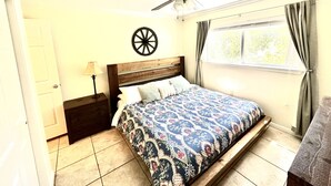 A bedroom with a bed, a ceiling fan, a window with curtains, a wall clock, and a nightstand. - The Blue Llama- on the Guadelupe river! 2 pools, 1 heated, 4 hot tubs (New Braunfels)