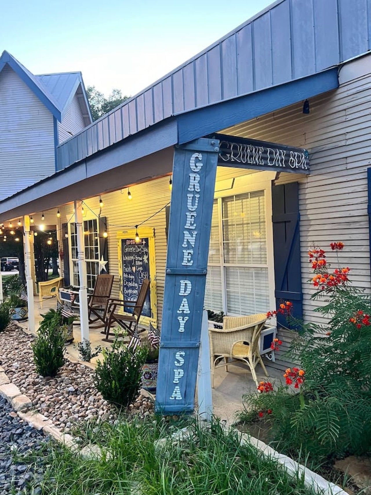 A spa named Gruene Day Spa with a covered outdoor seating area and a signboard.