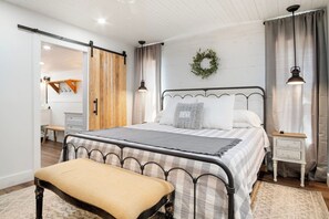 A bedroom with a bed, bench, bedside tables, and a wardrobe with a sliding door.