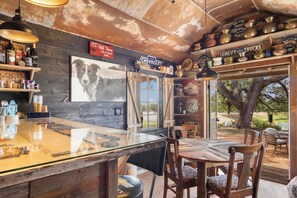 A rustic bar area with wooden shelves, a Chevrolet memorabilia collection, and a large dog portrait.
