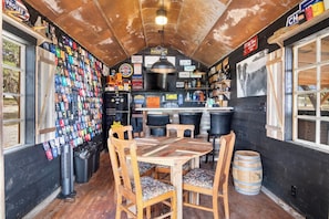 Eine rustikale Bar mit einem Holztisch und -stühlen, einem Kühlschrank und einer Wand mit verschiedenen Andenken.
