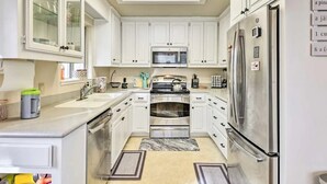 Una cocina moderna con armarios blancos, electrodomésticos de acero inoxidable y una isla central.