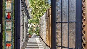 A narrow pathway leading to a building with a wooden fence and a glass door. - Downtown Sebastopol Studio (Sebastopol)