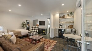 A modern hotel room with a large bed, a sofa, a dining table, and a kitchen area. - Downtown Sebastopol Studio (Sebastopol)