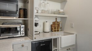 A compact kitchen with a Breville toaster oven, a Breville microwave, a Breville toaster, and a black dishwasher. - Downtown Sebastopol Studio (Sebastopol)