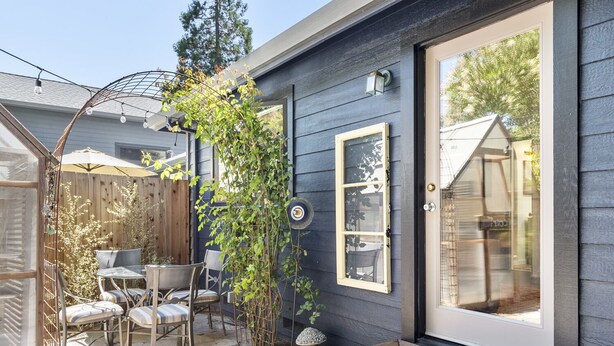 A patio with a table and chairs, a wooden deck, and a large window. - Downtown Sebastopol Studio (Sebastopol)