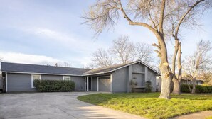 Ein Bungalow mit Garage, Auffahrt und Rasen mit Bäumen.