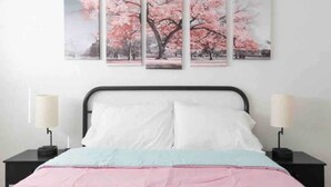 Ein Schlafzimmer mit einem Bett, zwei Nachttischen und einer Wandarbeit mit Kirschblüten.