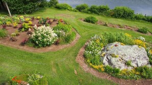 Un jardín ajardinado con un estanque, que presenta diversas plantas y una roca grande.