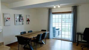 Una habitación amplia con una gran mesa de madera y sillas, una ventana con cortinas y obras de arte en la pared.
