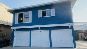 Una casa de dos pisos con fachada azul y tres puertas de garaje blancas.