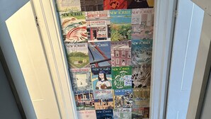 A hallway with a wall covered in various New York Times and The New Yorker magazine covers. - Spacious 5 Bedroom House On Double Lot In Lakeside One Block From The Lake! (Lakeside Marblehead)