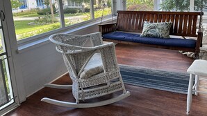 A sunroom with a rocking chair, a sofa, and large windows. - Spacious 5 Bedroom House On Double Lot In Lakeside One Block From The Lake! (Lakeside Marblehead)