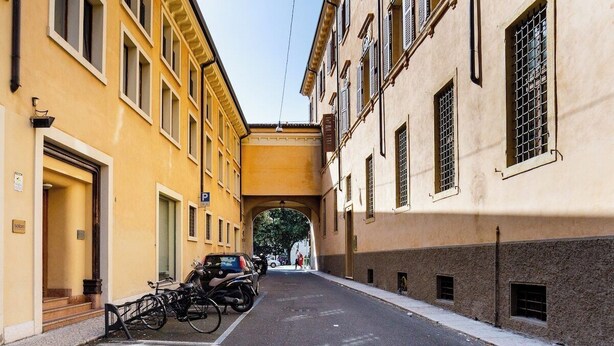 A narrow street with yellow buildings, a covered passageway, and parked bicycles. - MyArenaVerona － large apartment in the heart of Verona (Verona)