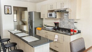 Una cocina compacta equipada con refrigerador, microondas, estufa y pileta.