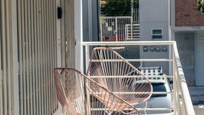 Un balcon avec une chaise en métal et un luminaire suspendu.