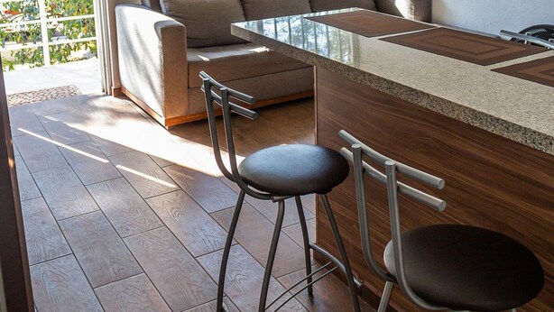 Un espace de vie moderne comprenant un canapé, une table basse et deux tabourets de bar.