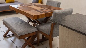 A dining area with a wooden table, grey upholstered chairs, a ceiling fan, and a flat-screen TV mounted on the wall.
