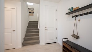 Una escalera que lleva a una puerta, un banco y un estante con ganchos y un cartel.