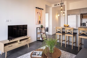 Un salon moderne doté d’un téléviseur à écran plat, de meubles en bois et d’un coin repas avec des chaises et une table.