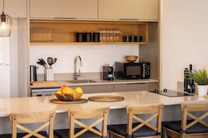 Une cuisine moderne dotée d’un îlot central, d’un four à micro-ondes, d’une machine à café et d’un évier.