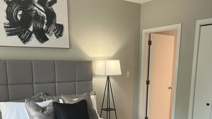 Ein Schlafzimmer mit einem großen Bett, einer Stehlampe und einer Tür zu einem anderen Raum.
