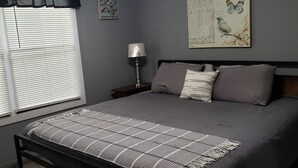 Une chambre à coucher avec un lit, un ventilateur de plafond, une table de chevet, une lampe et des œuvres d’art accrochées au mur.