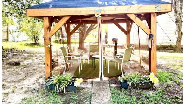 A wooden gazebo with a blue roof, featuring a table and chairs underneath.