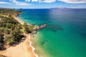 An aerial view of a coastal area with clear turquoise waters, a sandy beach, and a rocky shoreline. - Kihei Akahi D506 Beautiful - Oceans Views (Kihei)