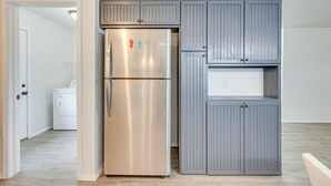 A kitchen with a stainless steel refrigerator, grey cabinets, and a laundry machine in the background. - Updated Home w/ Yard ~ 14 Mi to Quartz Mountain! (Mangum)