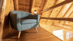 A room with a wooden ceiling, a blue armchair, and a lantern on the floor. - Hillside Haven - peaceful, private, pet friendly (Albany)