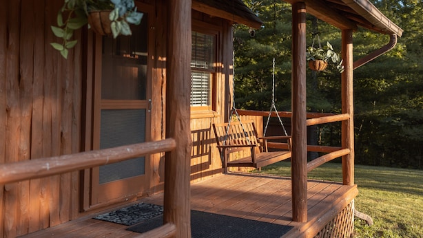 A wooden cabin with a porch, a swing, and hanging plants. - Hillside Haven - peaceful, private, pet friendly (Albany)