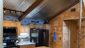 A modern kitchen with a large island, wooden cabinets, and stainless steel appliances.