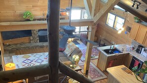 A wooden interior with a dining area, kitchen, and a staircase.
