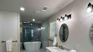 A modern bathroom with a large bathtub, a walk-in shower, and a vanity with a mirror. - The CanyINN (Canyon)