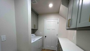 A narrow hallway with a white toilet, a small sink, and a door leading to another room. - The CanyINN (Canyon)