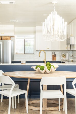 Una cocina moderna con armarios blancos, una isla de madera y una lámpara colgante original.