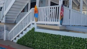 Ein weißes Gebäude mit Schwimmbad und einer grünen Hecke.